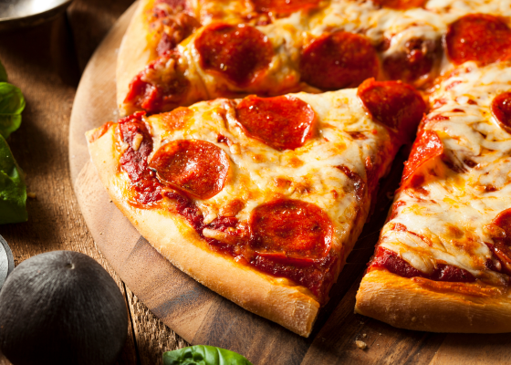Fresh pepperoni pizza with a slice pulled out on a wooden surface, representing artisan pizzerias in Aberdeen, NC.