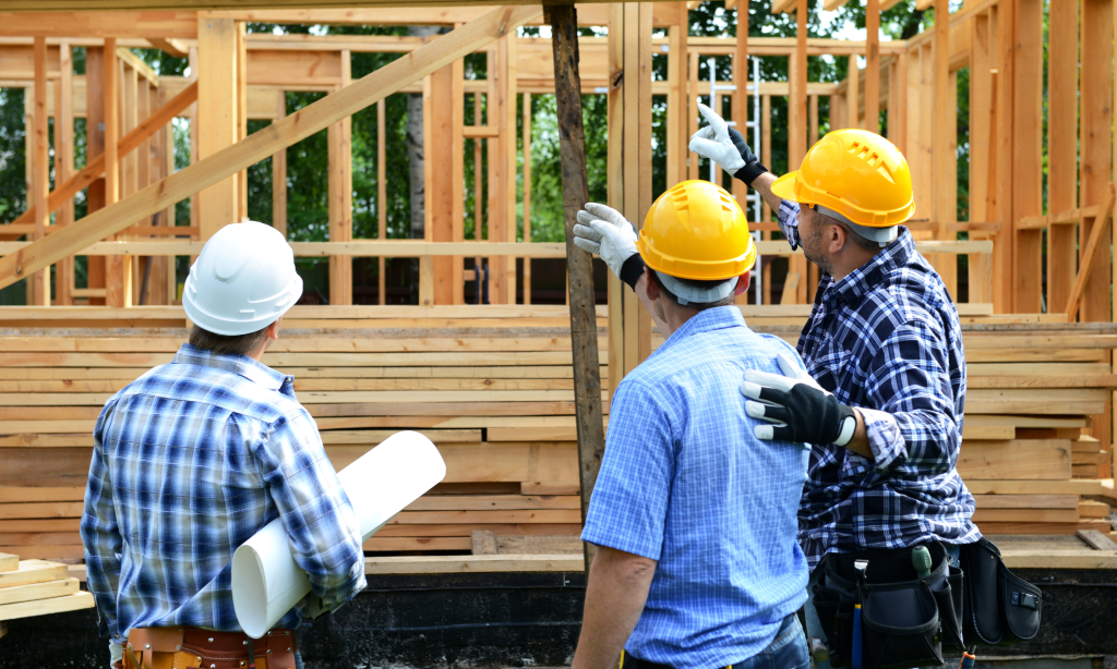 Construction workers with helmets reviewing new construction home plans near Ft. Bragg
